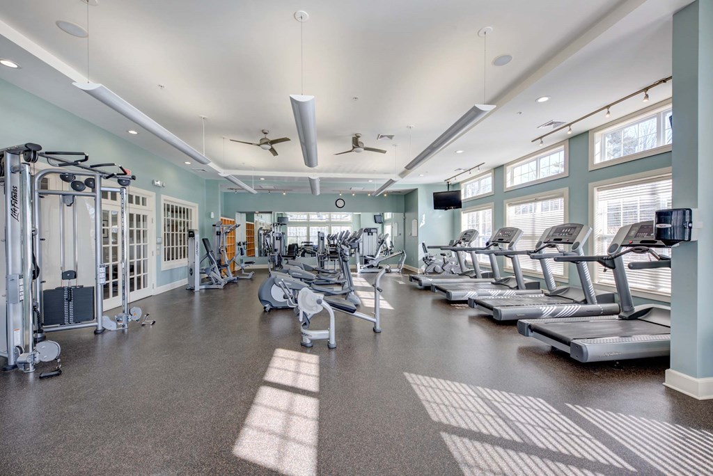 a gym with cardio equipment and windows