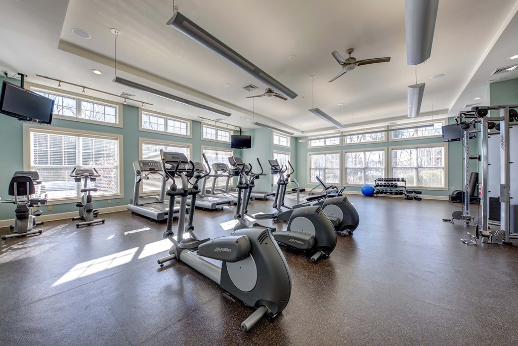 a gym with treadmills and other exercise equipment in a large windowed room