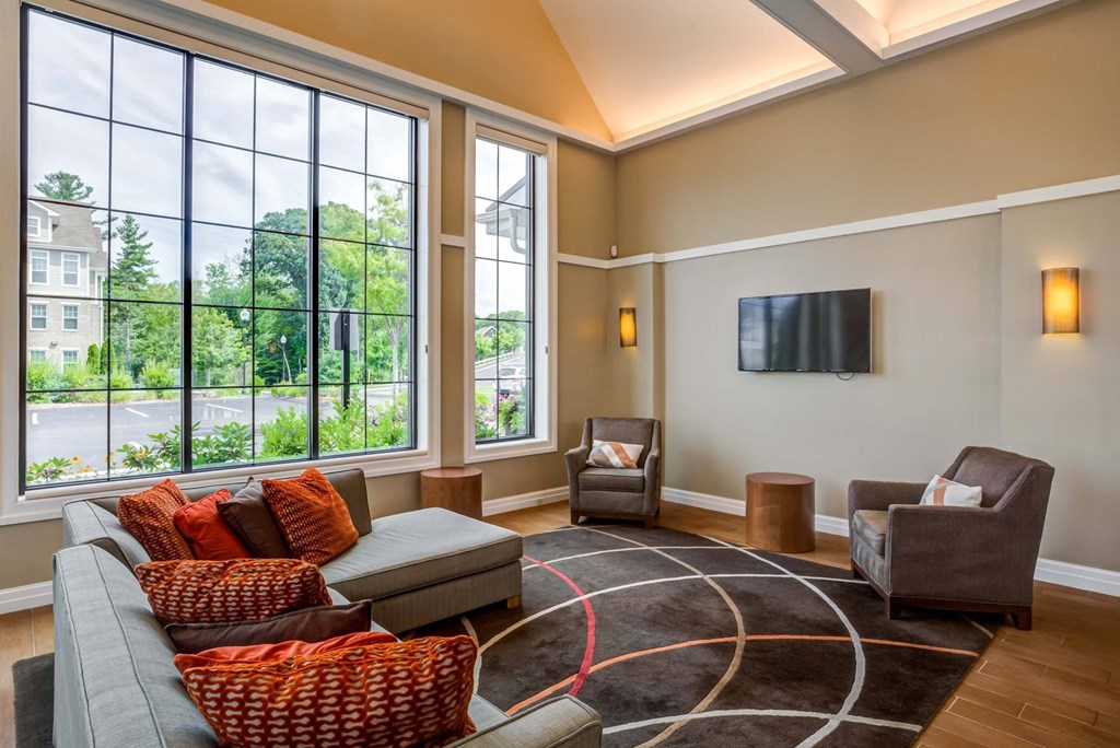 a living room with a couch and chairs and large windows