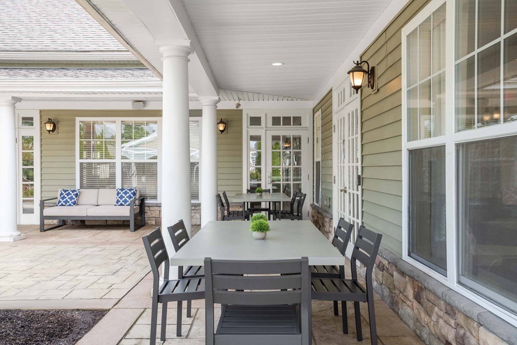 a covered patio with a white table and chairs
