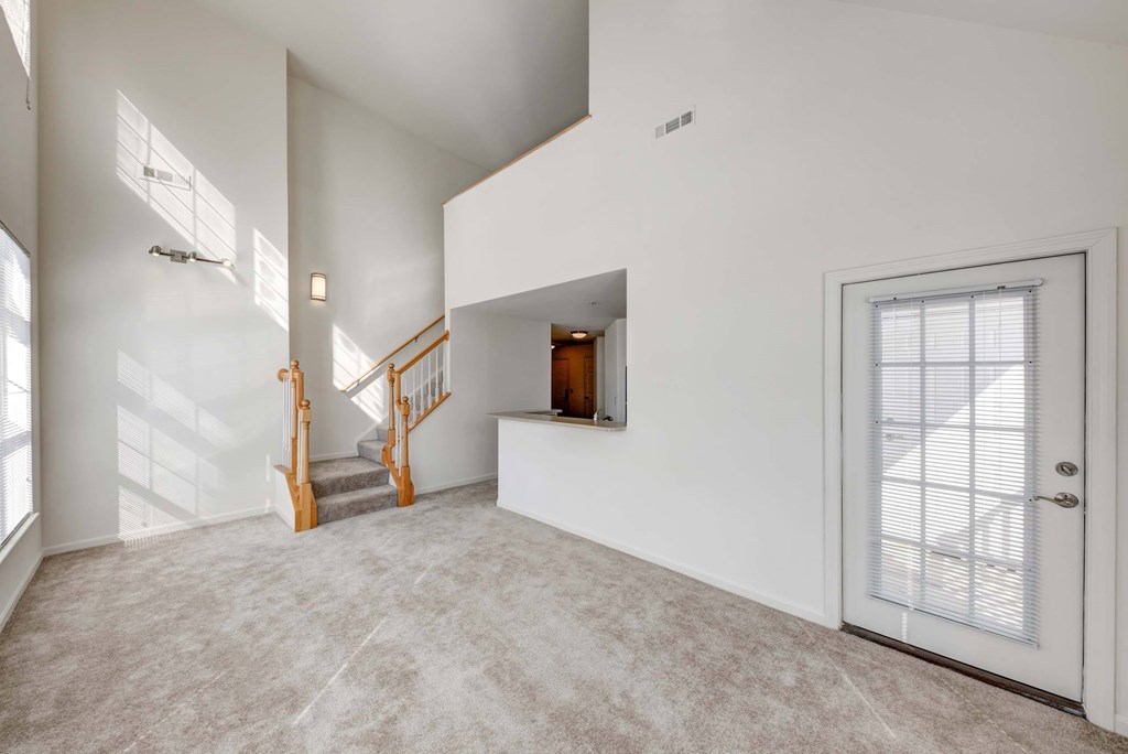 an empty living room with a door and a staircase