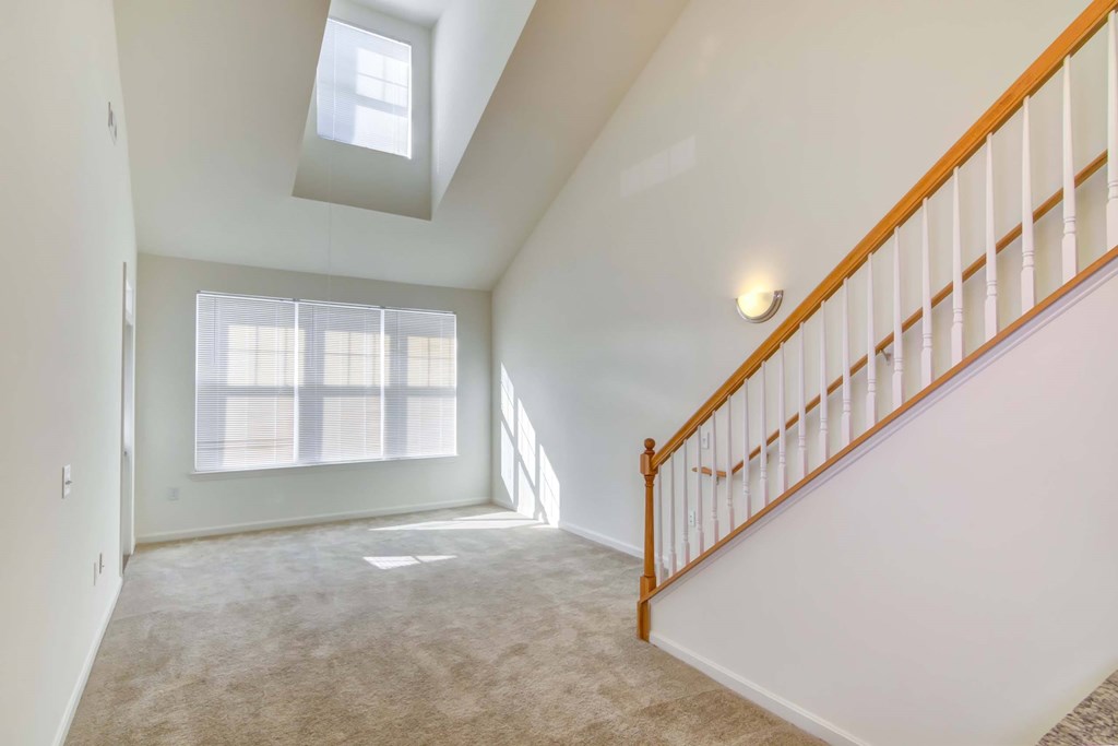 a room with a staircase and a window and a carpeted floor