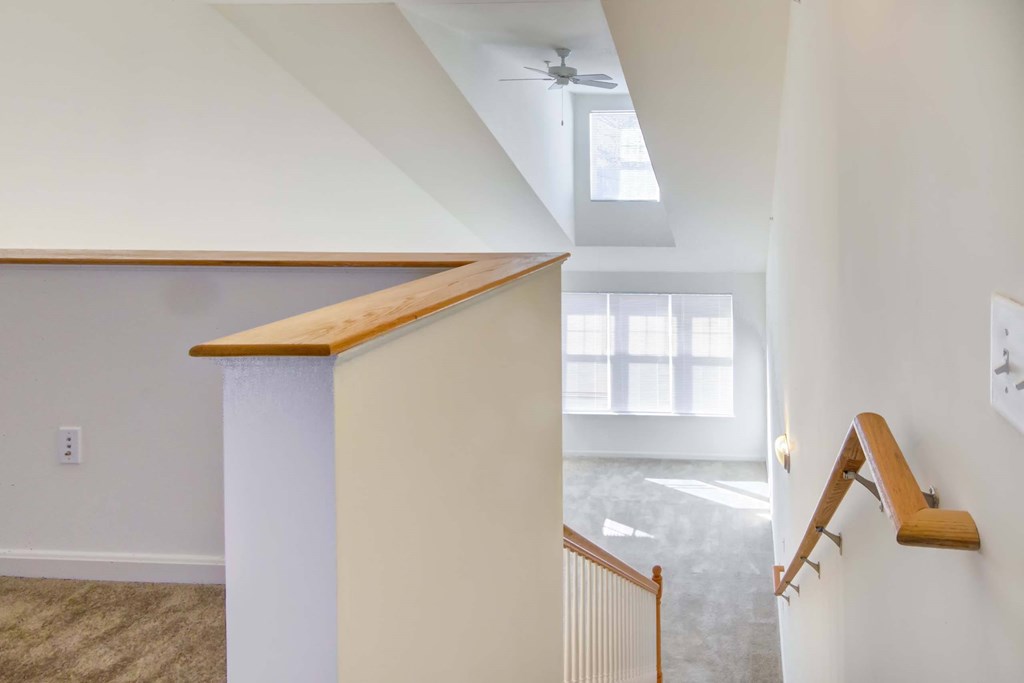 a staircase in a home with white walls and a ceiling fan