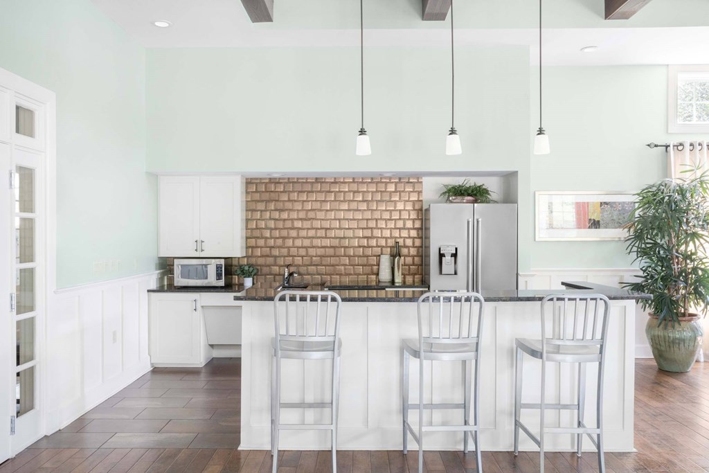 a white kitchen with bar stools and a brick wall