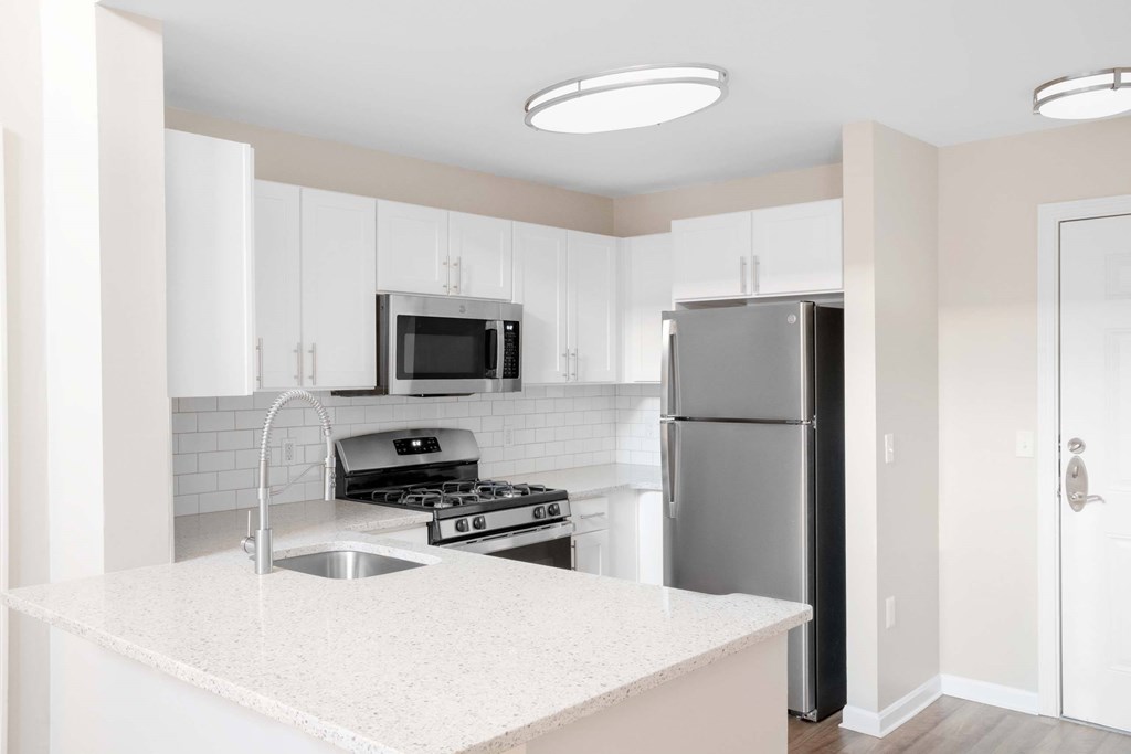 a white kitchen with stainless steel appliances and a counter top