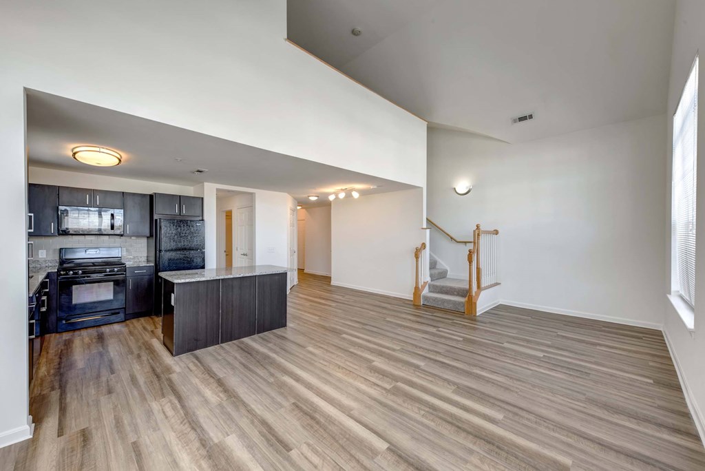 a renovated living room with a kitchen and a staircase