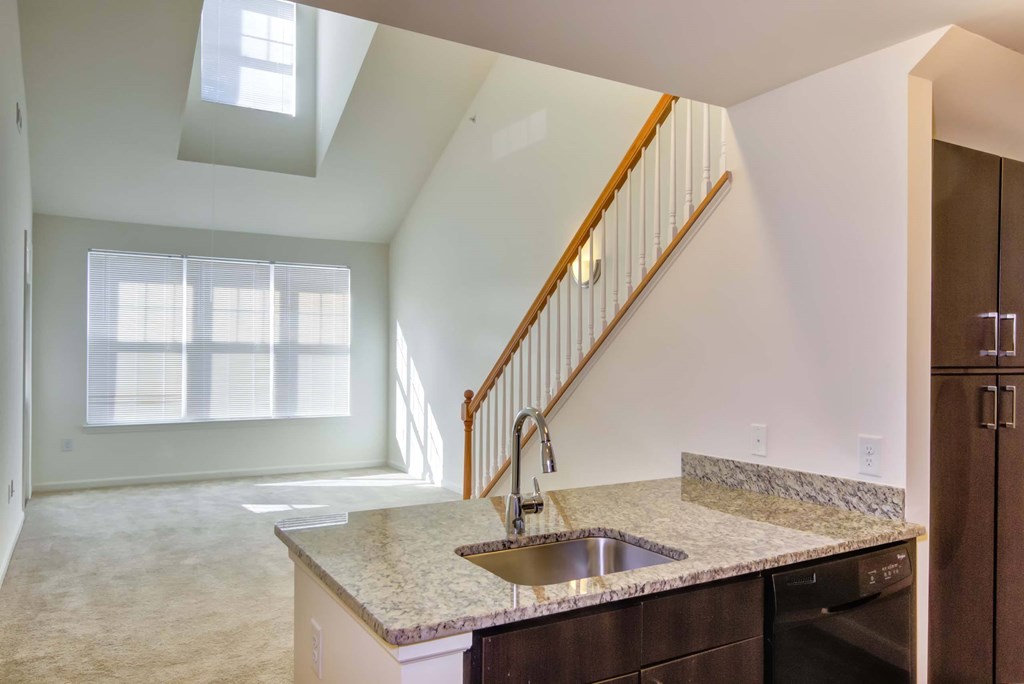 an empty kitchen with a sink and a stairwell