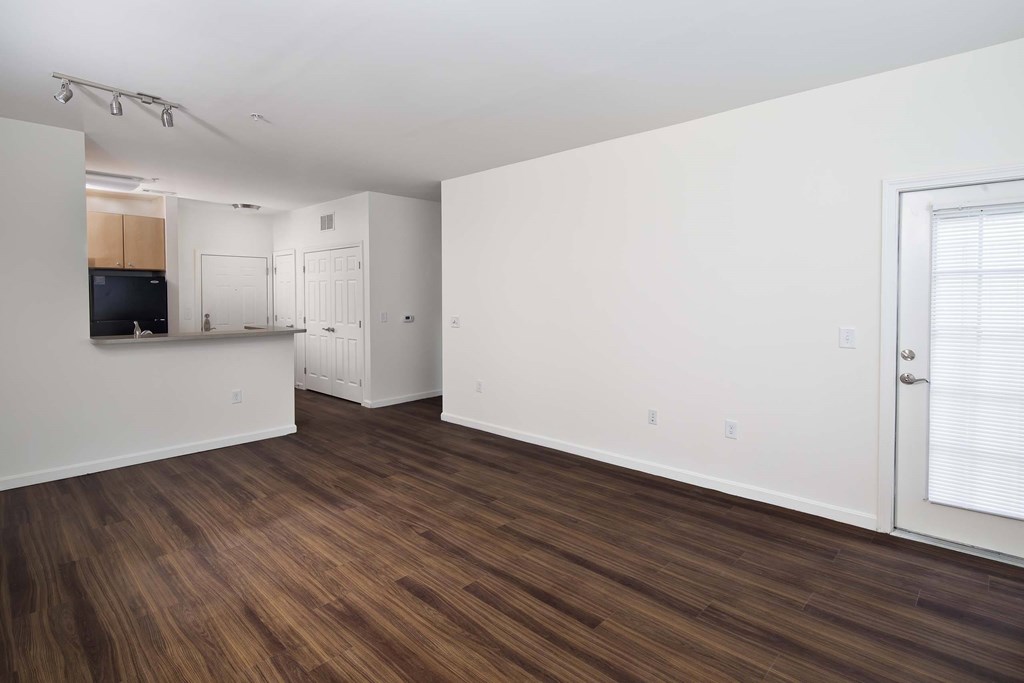 a living room and kitchen with wood flooring and white walls