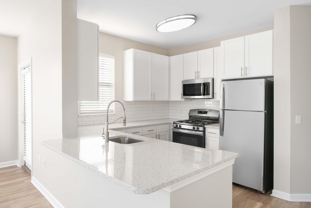 a white kitchen with an island and stainless steel appliances
