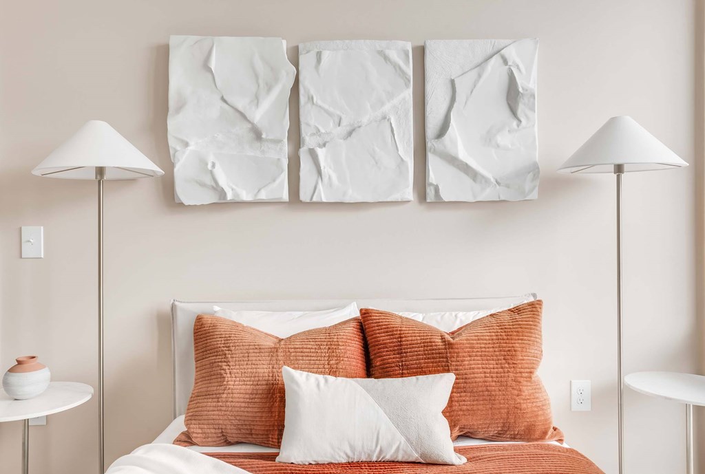 a bedroom with white walls and orange bedding
