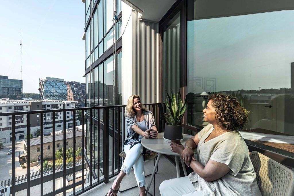two women sitting at a table on a balcony