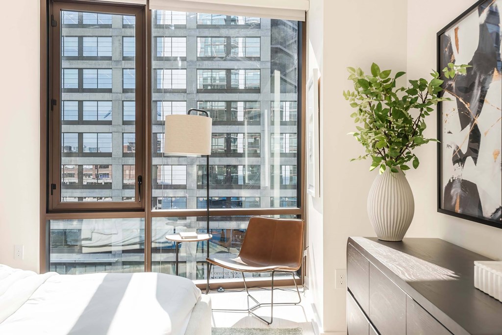 a bedroom with a large window and a chair