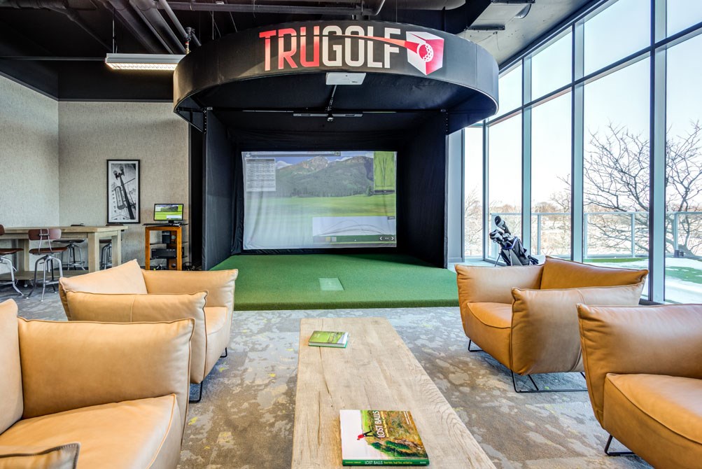 a living room with a golf simulator and a tv on the wall