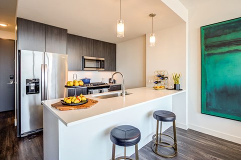 kitchen with stainless steel appliances and counter tops and two stools
