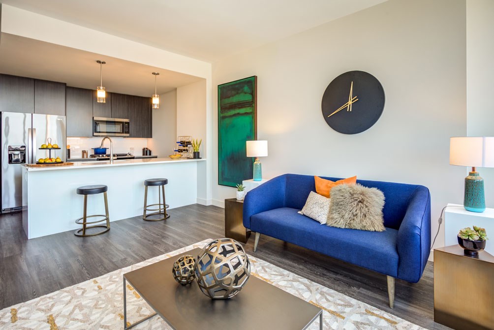 a living room with a blue couch and a kitchen with a bar