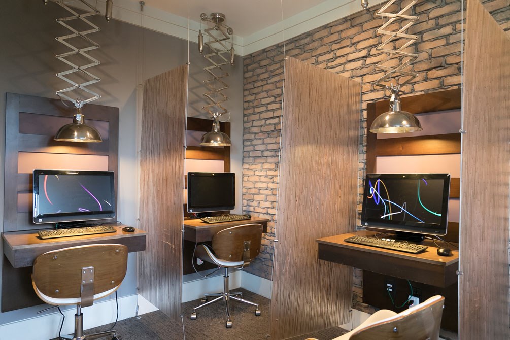 a home office with two computers and a brick wall