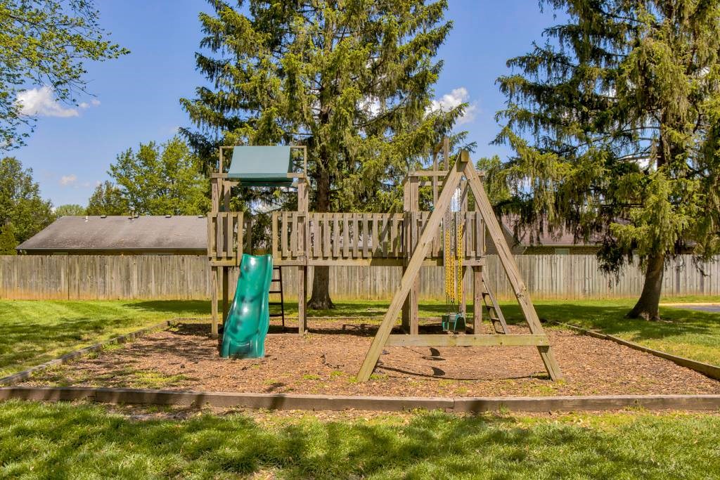 a swing set in a backyard with a wooden fence