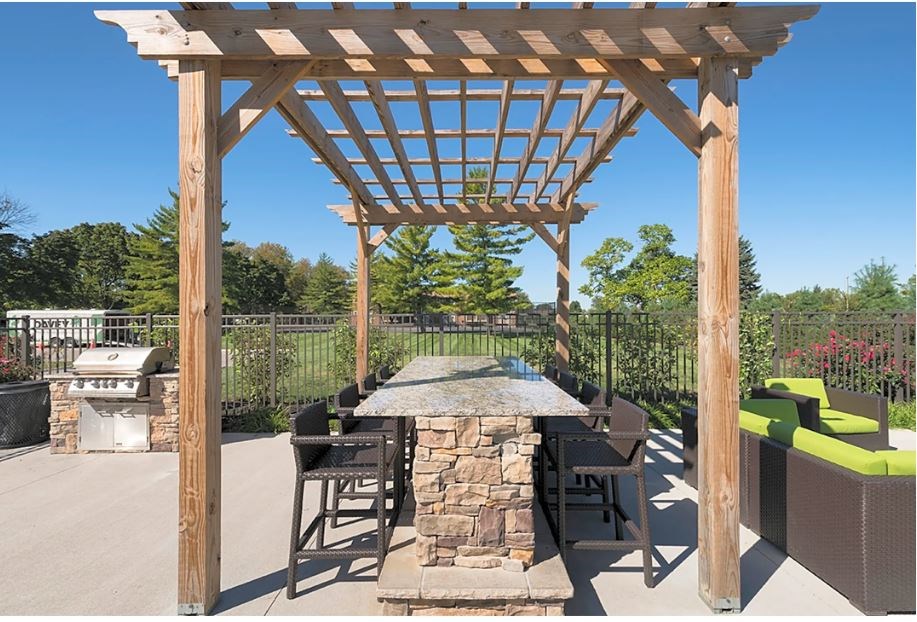 a patio with a stone table and a wooden pergola