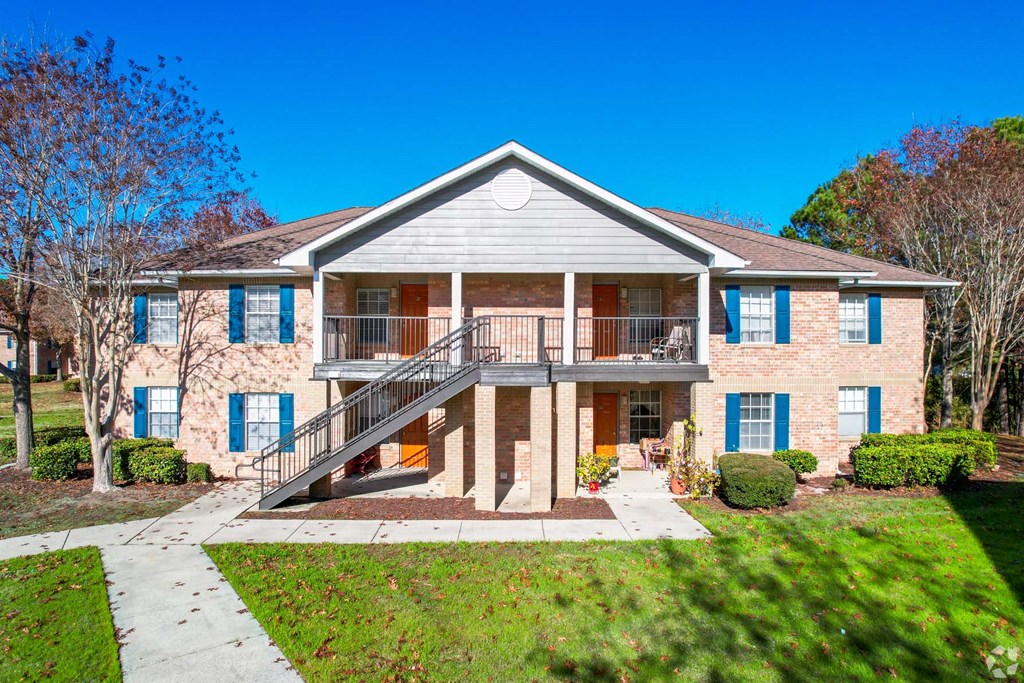 the front of a brick house with a balcony and a staircase