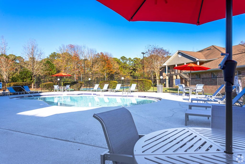 a pool with chairs and umbrellas next to a house