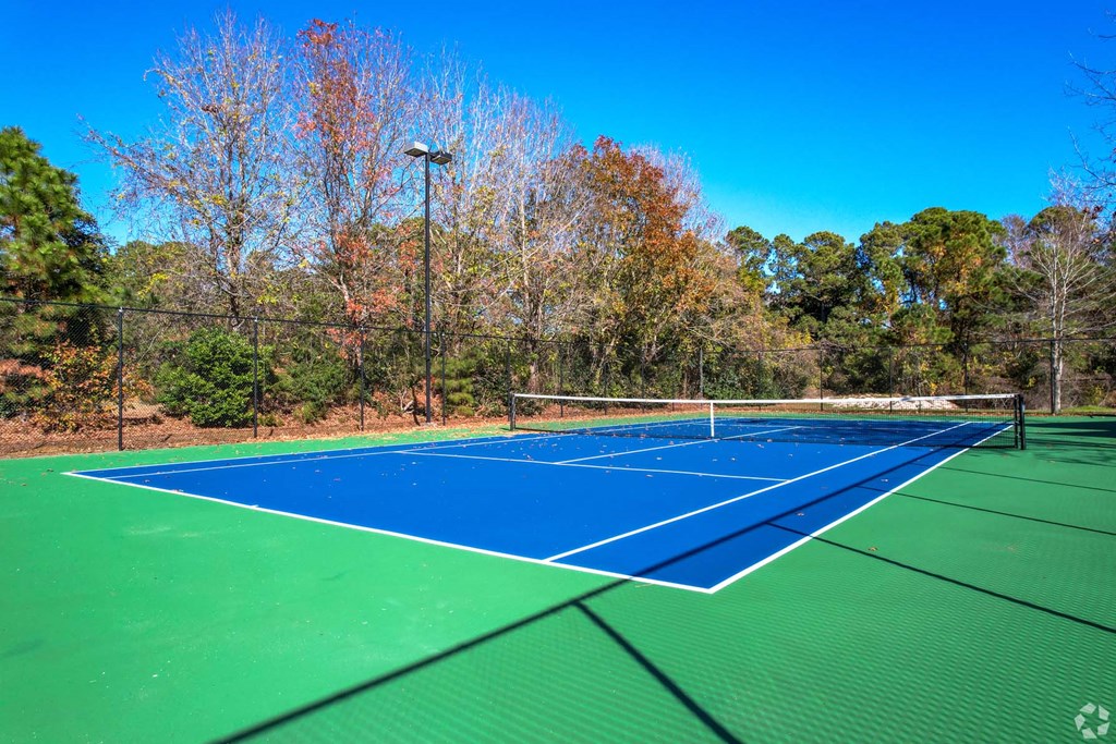a tennis court with blue and green turf and a fence