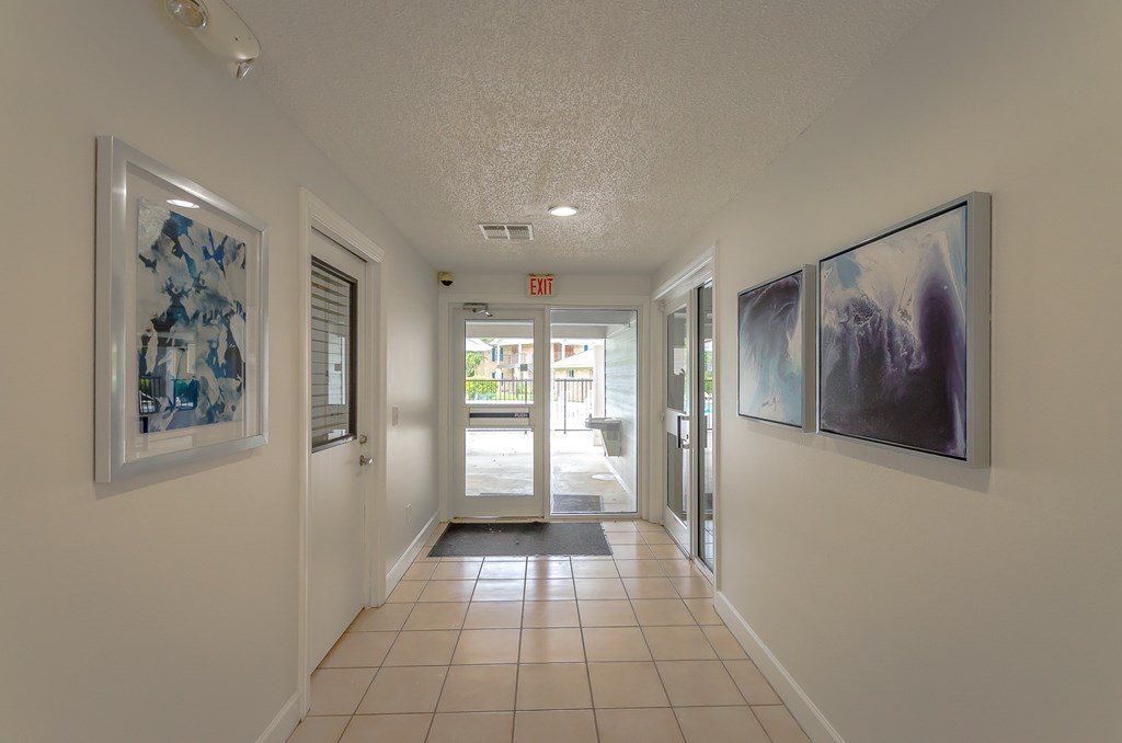 a hallway with paintings on the wall and a tiled floor
