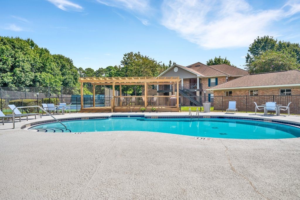 a swimming pool with chairs and a house in the background