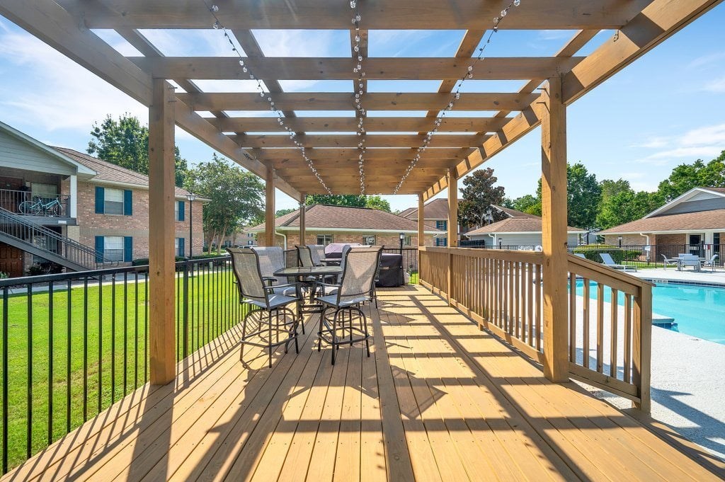 a covered deck with a pool and patio furniture