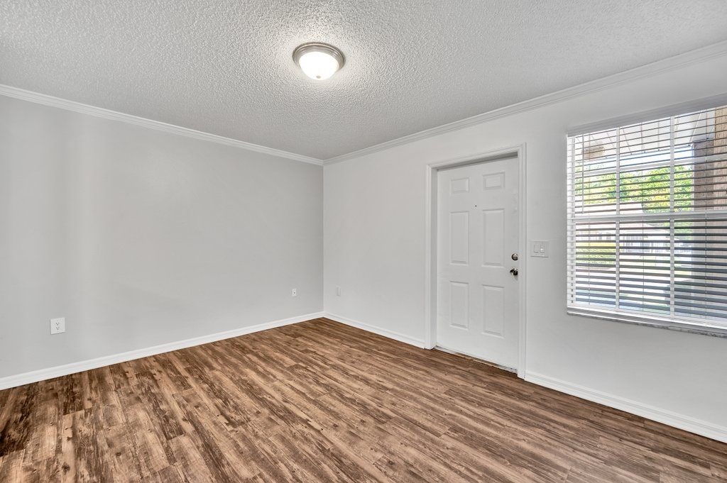 an empty living room with a window and a white door