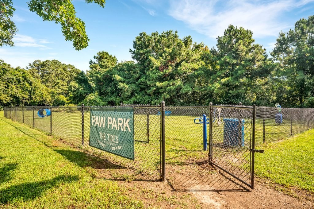 a park with a fence and a sign for paw park