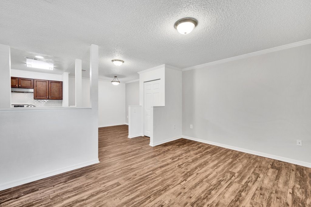 an empty living room and kitchen with wood flooring