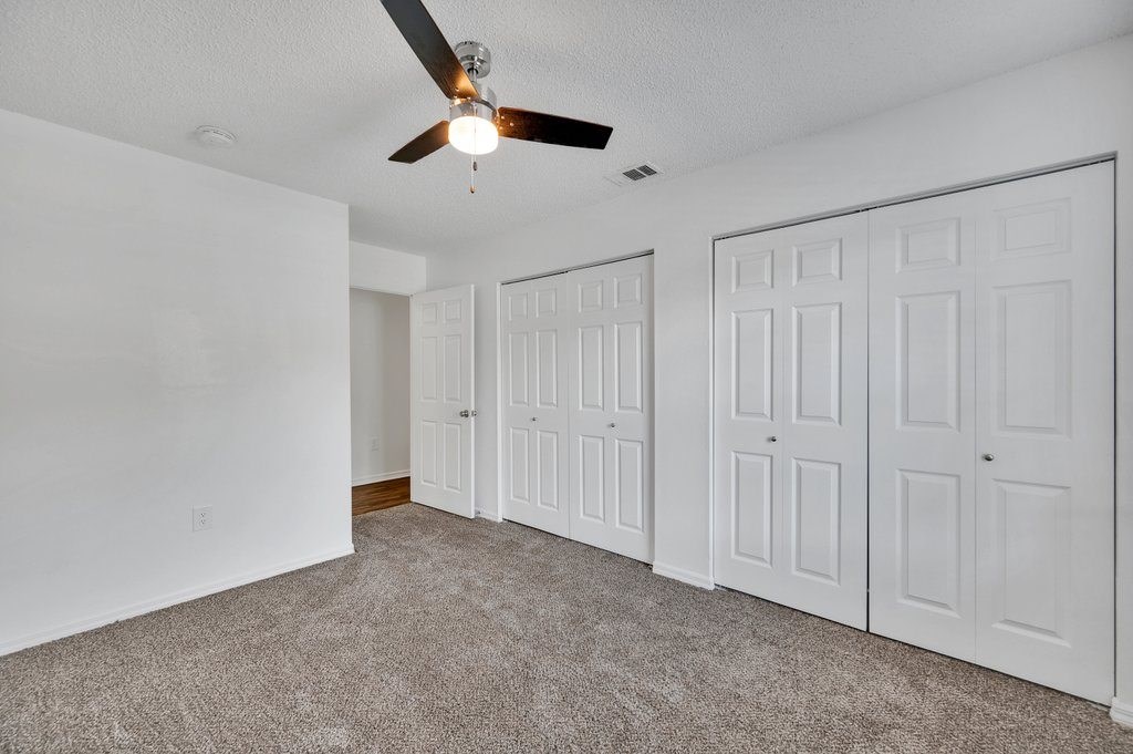 a bedroom with a ceiling fan and white closets