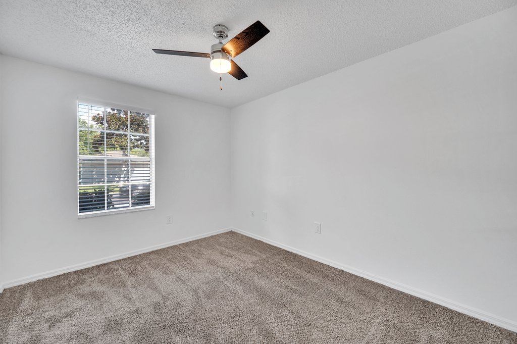 an empty bedroom with a ceiling fan and a window
