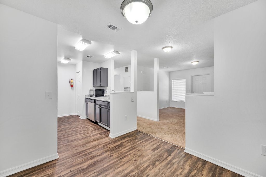 an open kitchen and living room with white walls and wood flooring