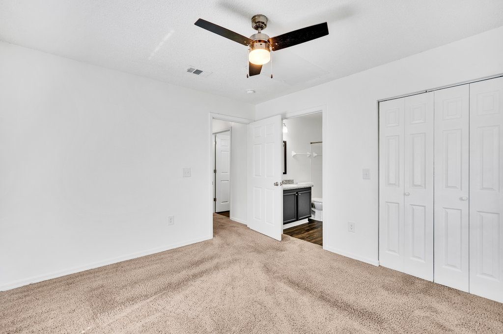 a living room with carpet and a ceiling fan