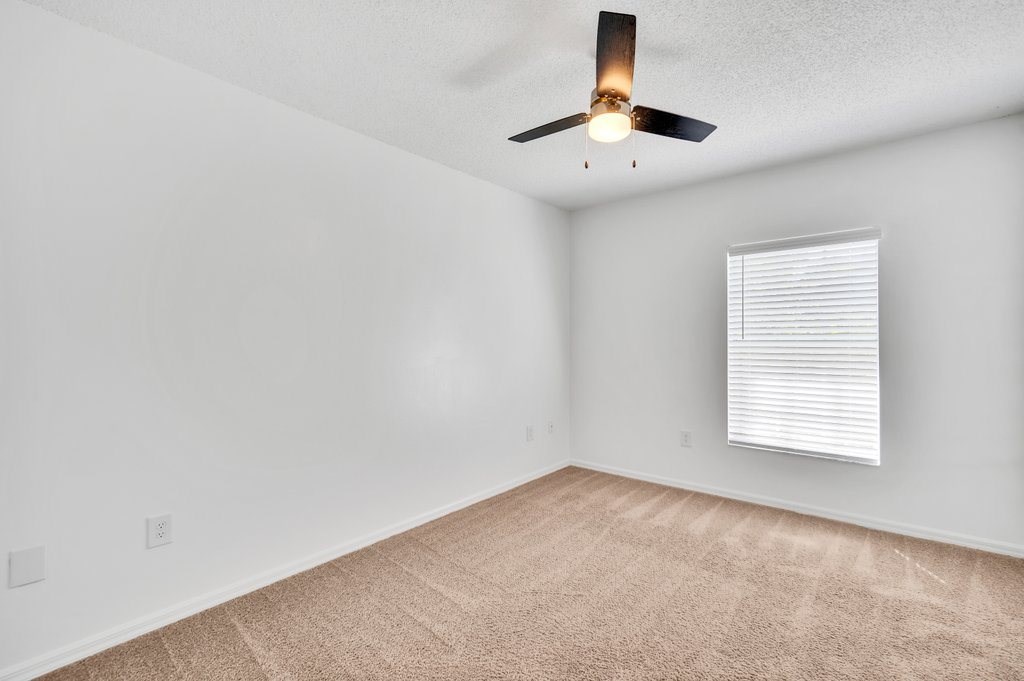 an empty living room with a ceiling fan and a window