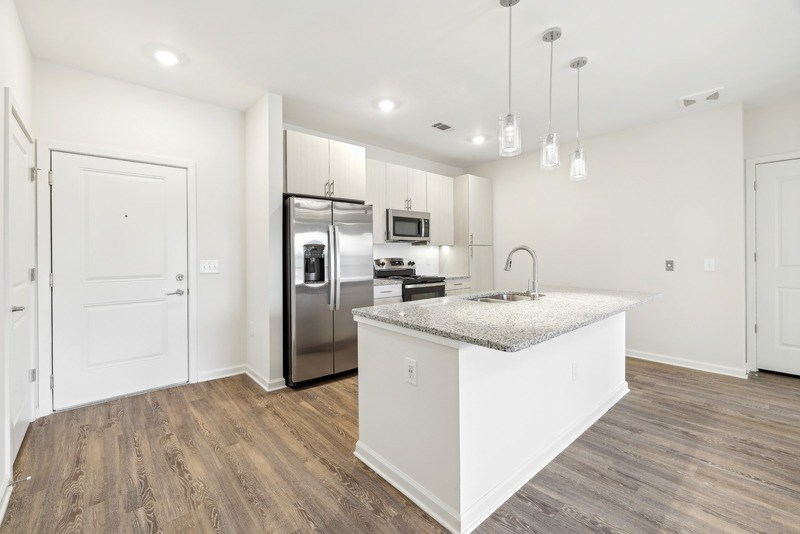 a white kitchen with stainless steel appliances and a marble counter top