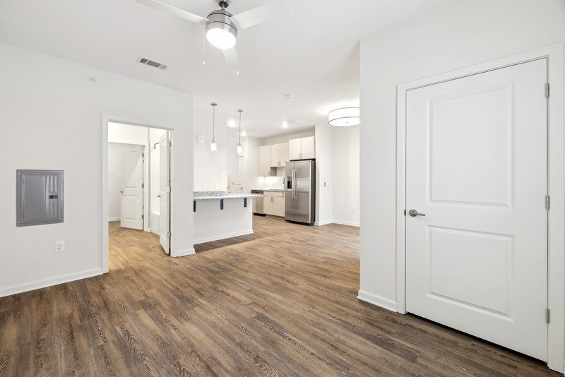 a living room and kitchen with white walls and wood flooring