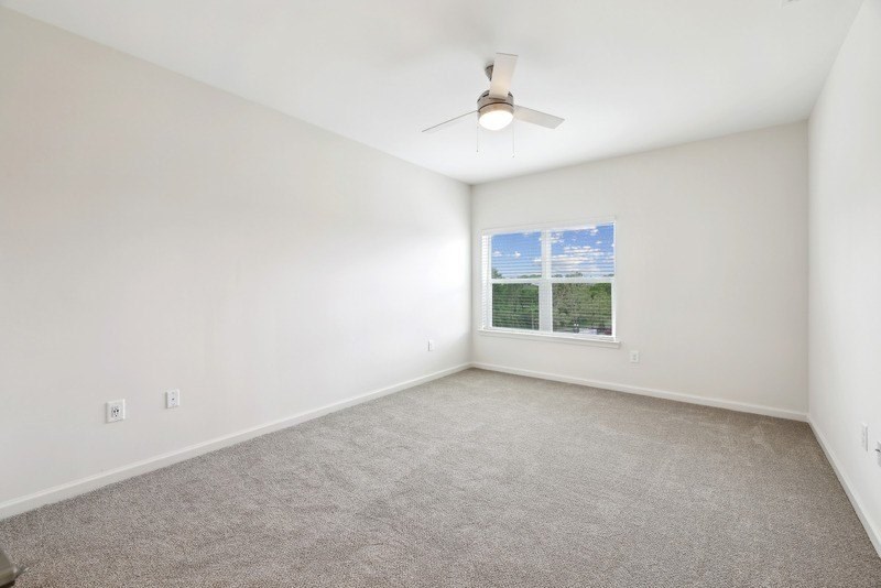 an empty living room with a ceiling fan and a window