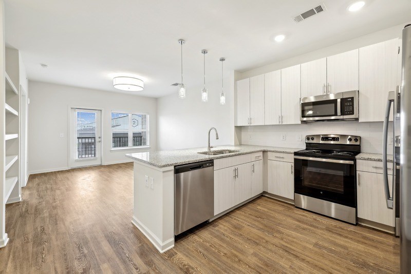 an empty kitchen with stainless steel appliances and white cabinets
