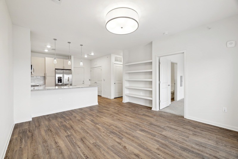 an open kitchen and living room with white walls and wood flooring