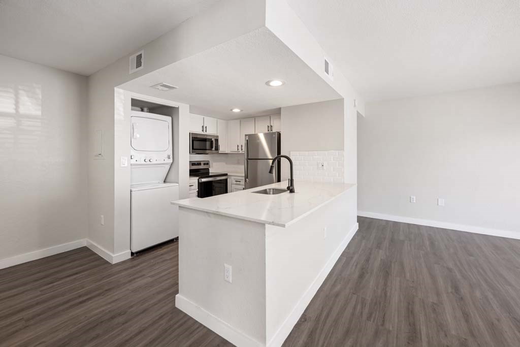 a white kitchen with a counter top and a refrigerator