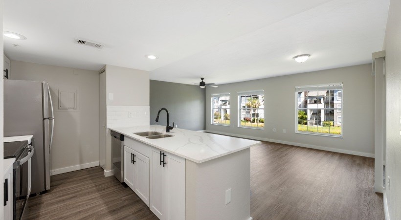 an empty kitchen with white counter tops and a stainless steel refrigerator