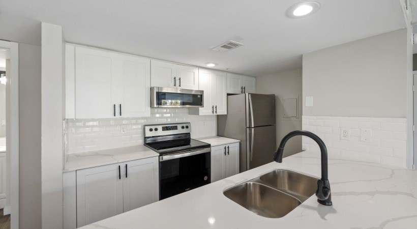 a kitchen with white cabinets and a sink and a refrigerator