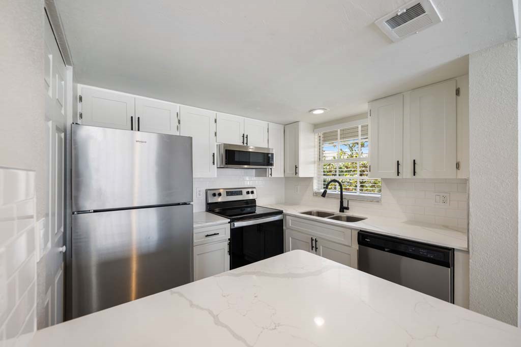 a white kitchen with stainless steel appliances and white counter tops