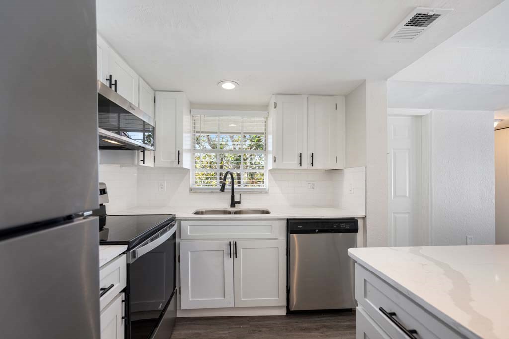 a kitchen with white cabinets and a sink and a window