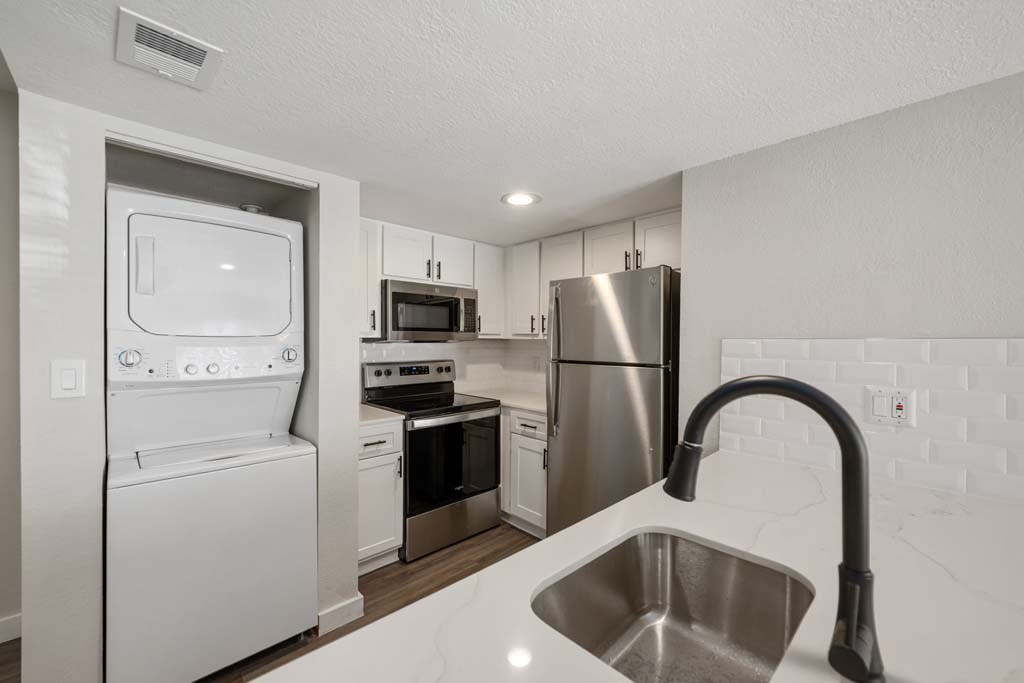 a white kitchen with stainless steel appliances and a sink