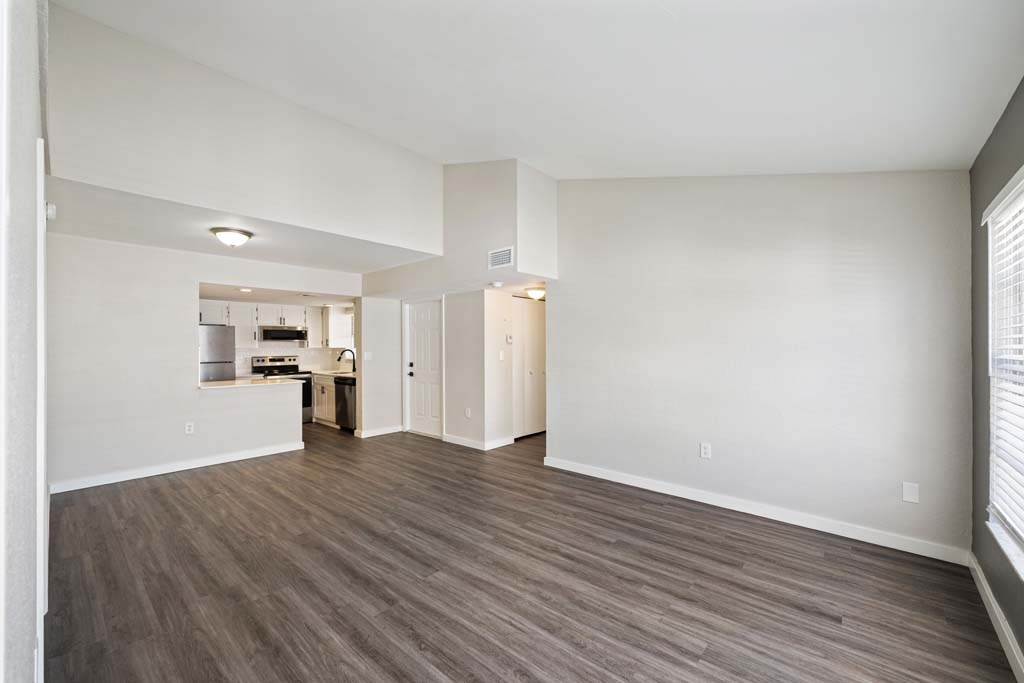 an empty living room and kitchen with wood flooring