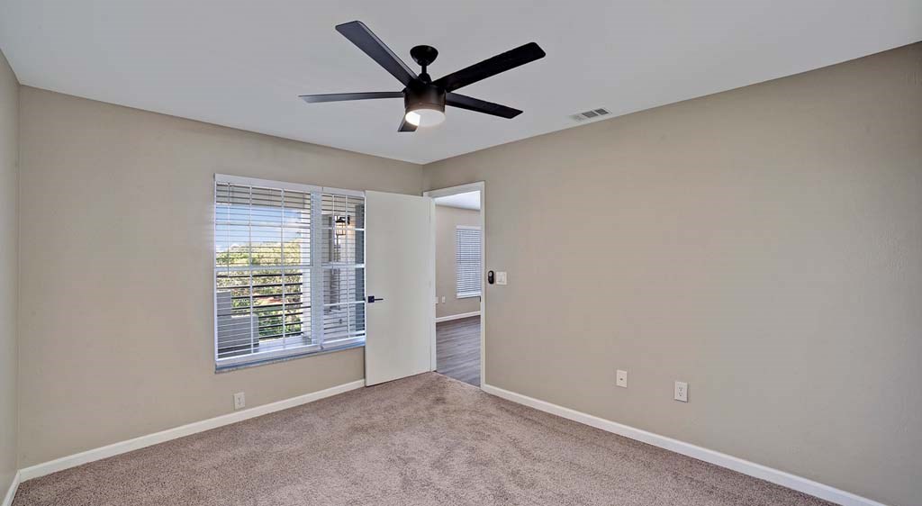 an empty room with a ceiling fan and a window