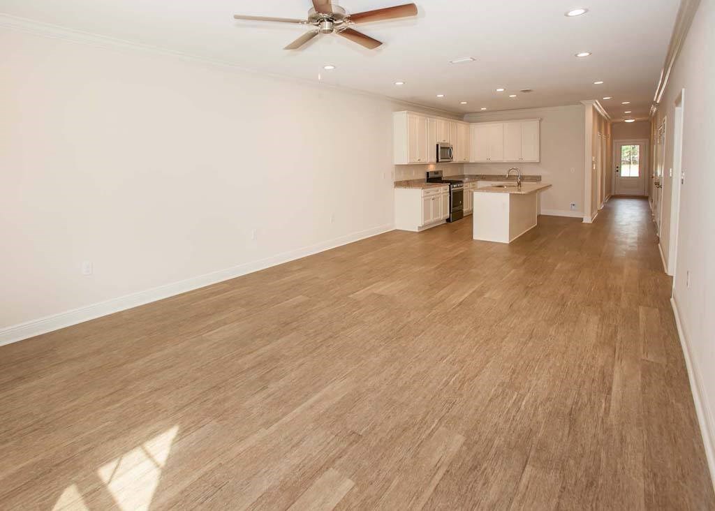 an empty living room and kitchen with a ceiling fan